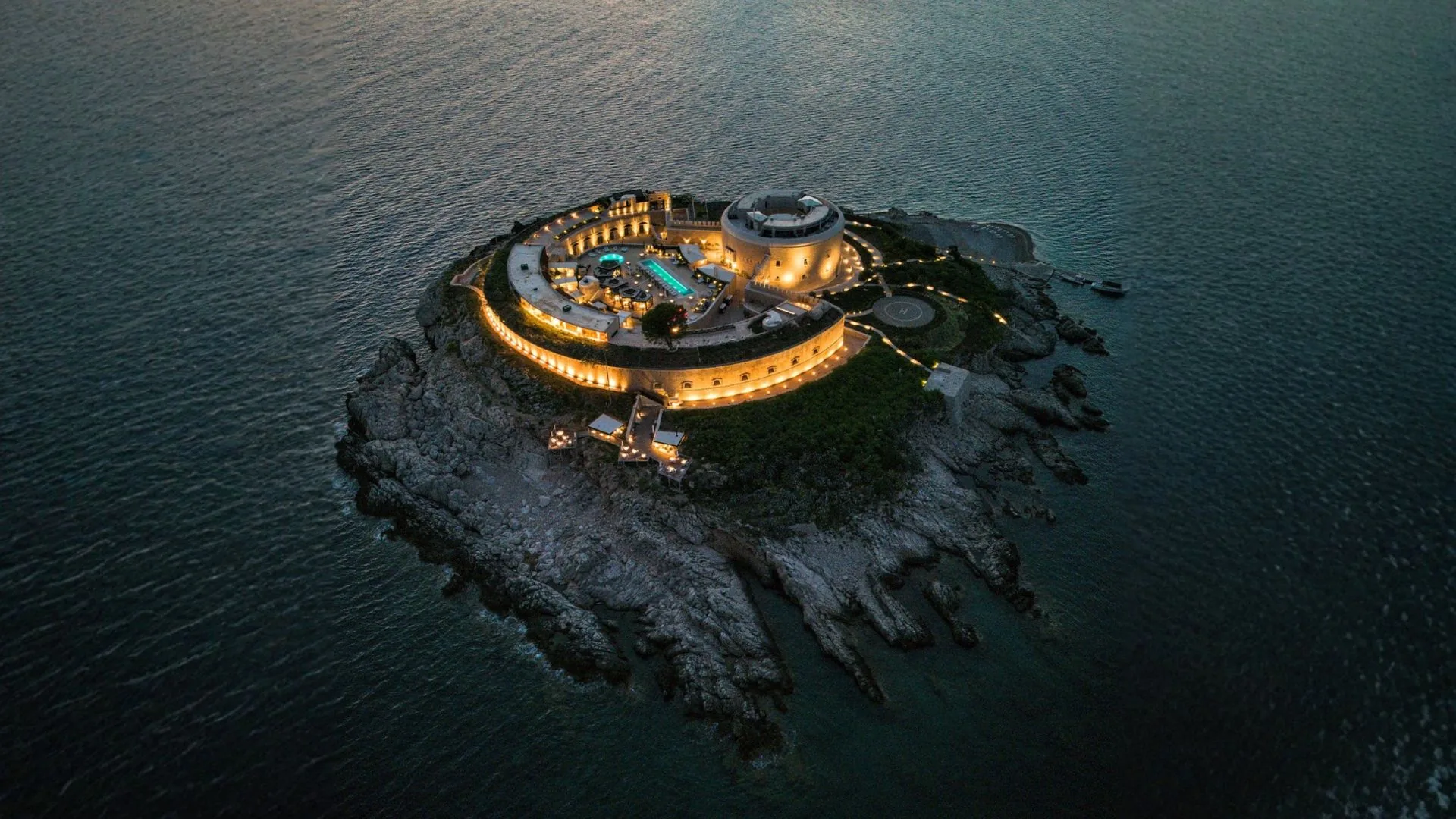Illuminated island retreat surrounded by the sea at dusk.